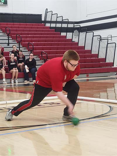 boy in glasses rolling a boccerball