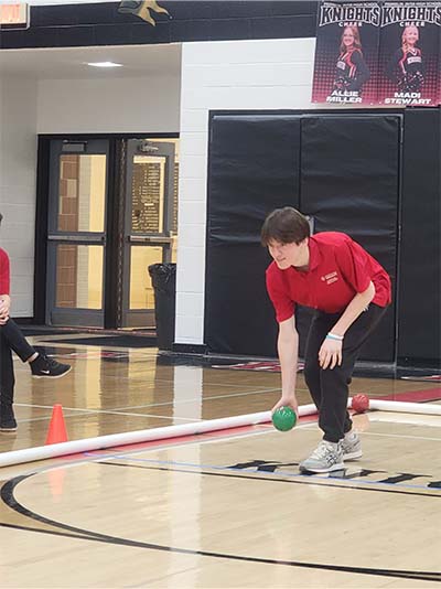 student rolling a green bocce ball