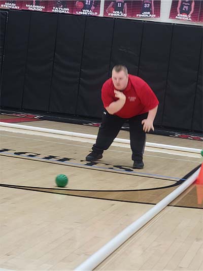 boy rolling a green bocce bal