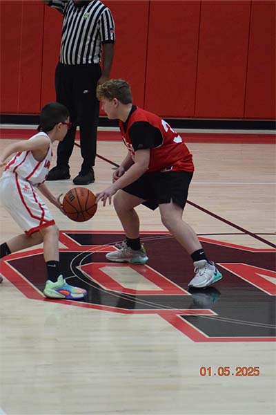 boy in red dribbling past a boy in white