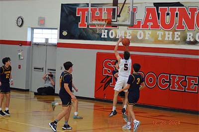 boy in white shooting a layup