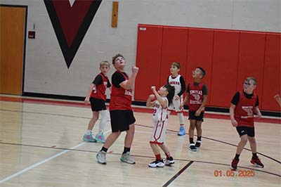 boys in red and white watching the basketball