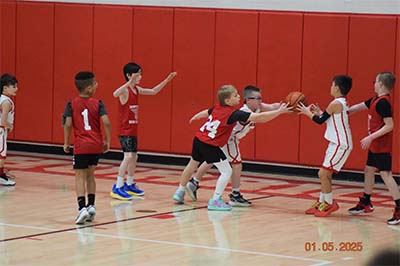 boy in red trying to steal a ball from a boy in white