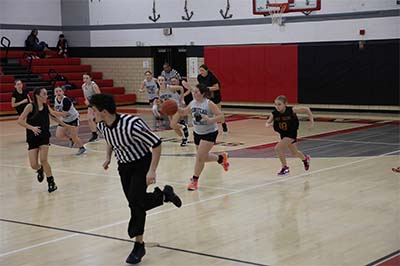 Girl in gray jersey running up the court