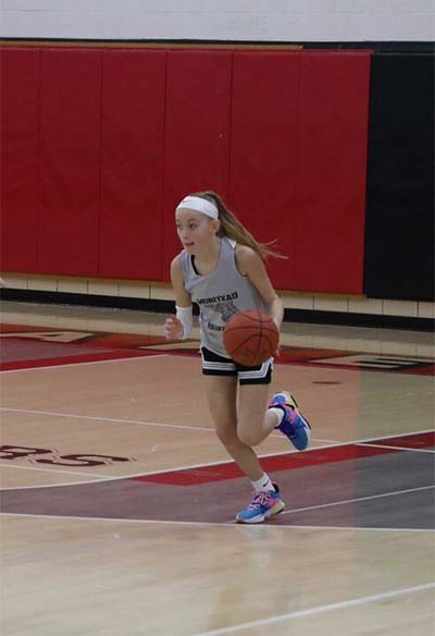 Girl in gray jersey and headband dribbling