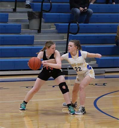 Girl in black keeping ball away from girl in white