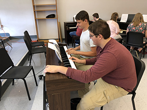 Six students playing on three pianos