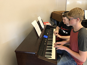 Two students playing a piano together