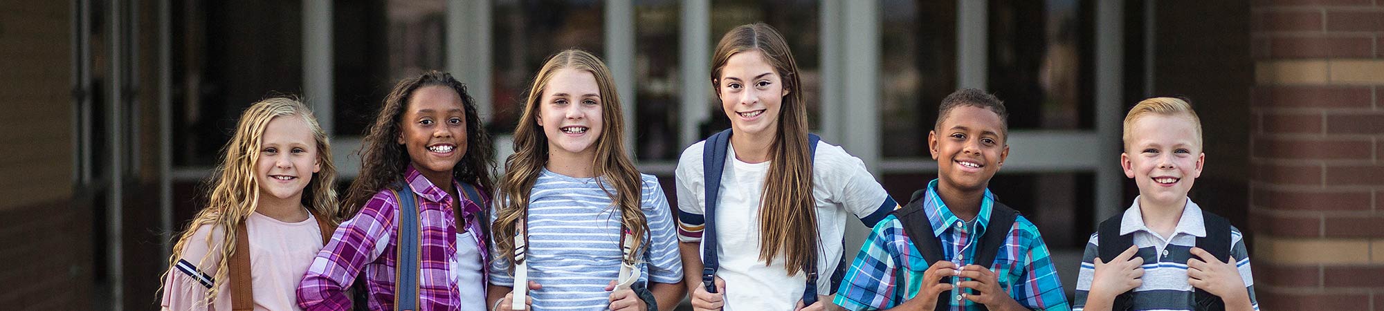 Students smiling in front of a school building