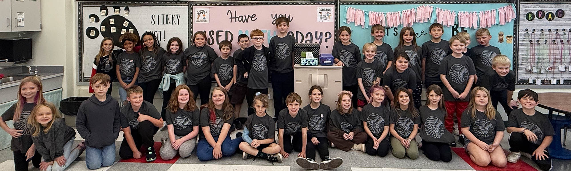 Group of happy students in black spirt t-shirts posing for a picture in a classroom