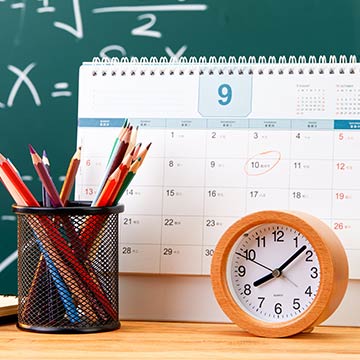 A clock and pencils in front of a calendar