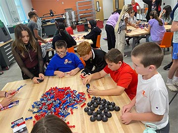 Students working on building cars with some small toy parts