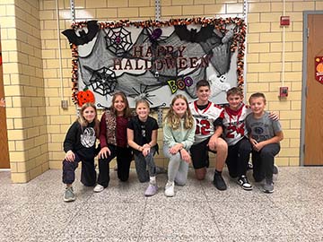 Students in front of a happy halloween decoration