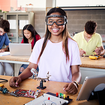 Happy student in a technology class wearing safety goggles