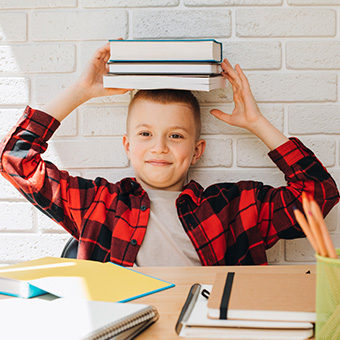 Elementary school boy balancing books on his head