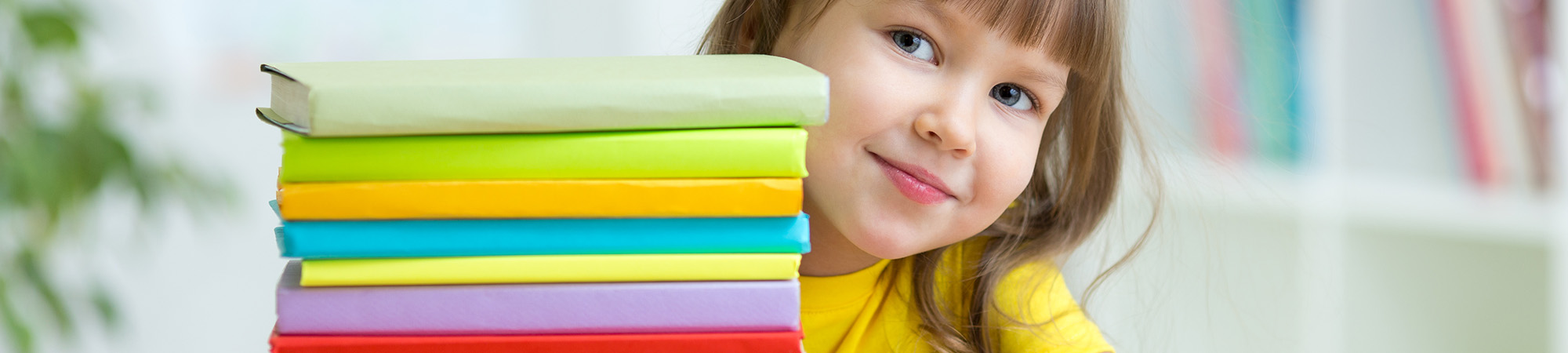 Elementary school girl looking from behind a stack of books
