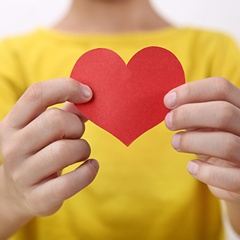 Student holding up a little red, paper heart