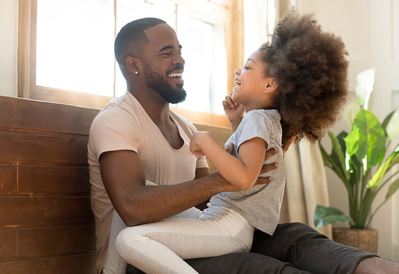 Father laughing with daughter on a bench