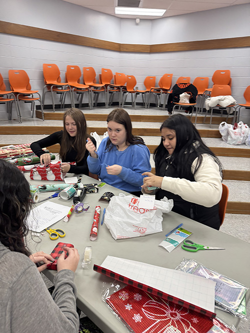 Students at a table helping by wrapping gifts