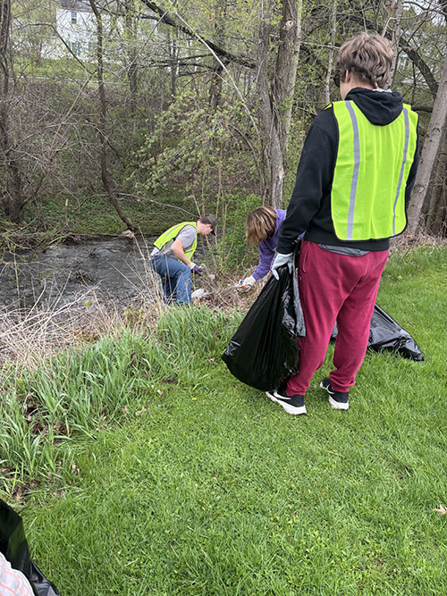 Students near a creek picking up trash