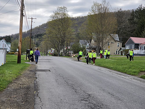 Students walking down a neighborhood road picking up trash for Earth Day
