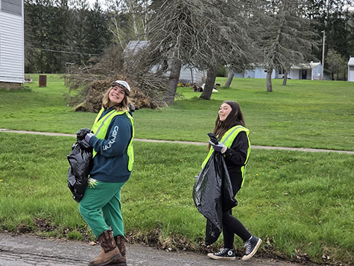 Two girls happily picking up trash on Earth Day