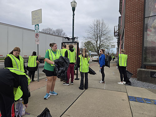 Group of student in safety vests holding trash bags