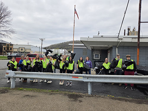 Group of students in safety vests posing for a photo after picking up trash on Earth Day