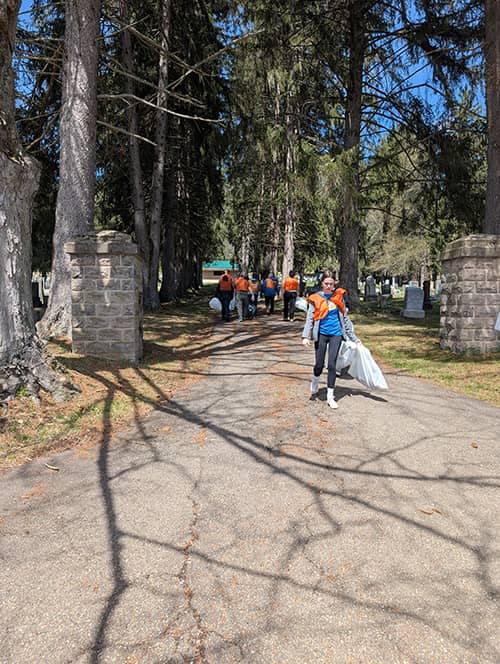 Student outside holding a trash bag