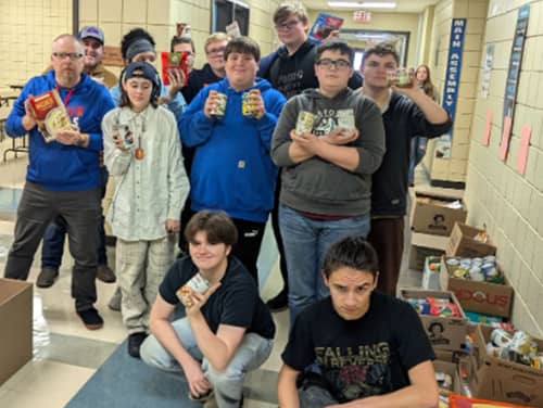 Students and teachers holding up donated food items