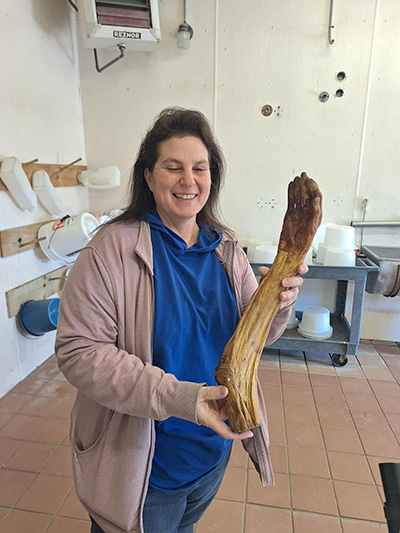 Teacher posing with arm and hand shaped item.