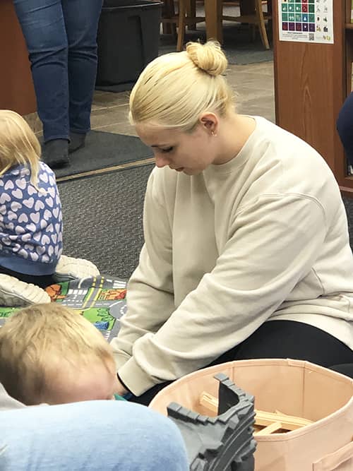 Seneca Highlands CTC student on the floor reading with children in the library