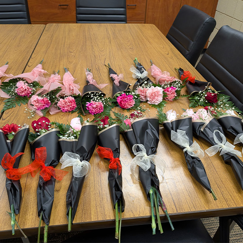 Several small rose and carnation arrangements on a table