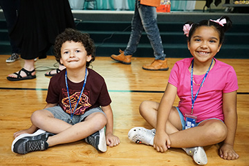 Two happy students sitting on the gym floor smiling for the camera