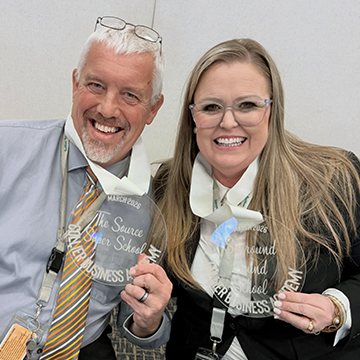 Two staff members smiling for the camera after receiving an award