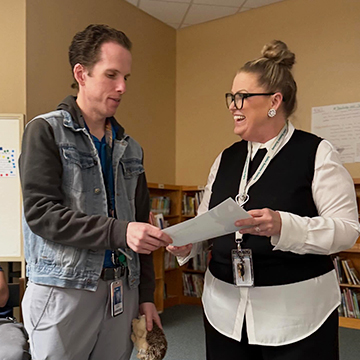 Principal handing an award to a staff member