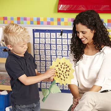 Student showing a flower to a teacher