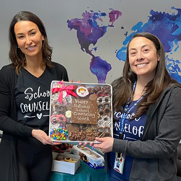 Mrs. Suzanne Lang and Ms. Dara Weiss holding up a tray of goodies