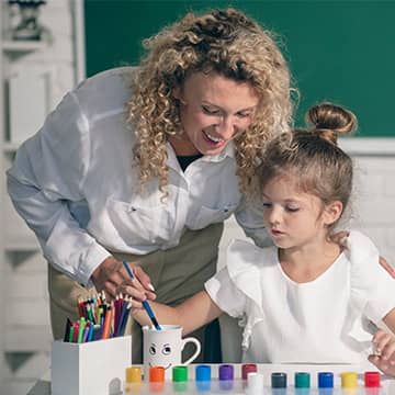 A teacher helping a student paint