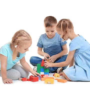 Three students stacking blocks together