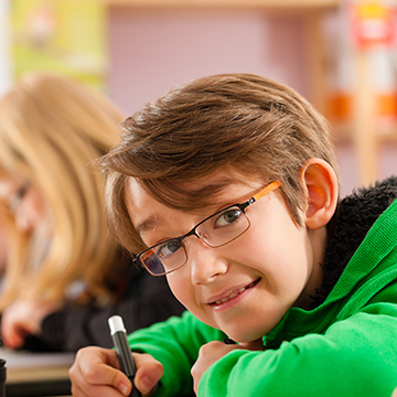 Student in green sweatshirt looking up at the camera