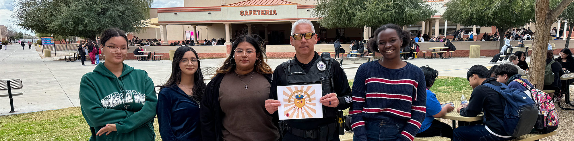 Students smiling with security guard outside by the cafeteria