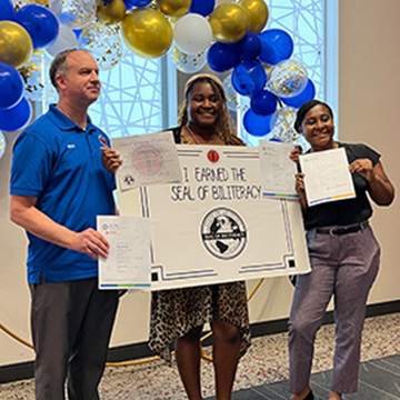Three people holding up certificates