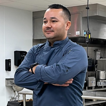 An adult with arms crossed in a kitchen