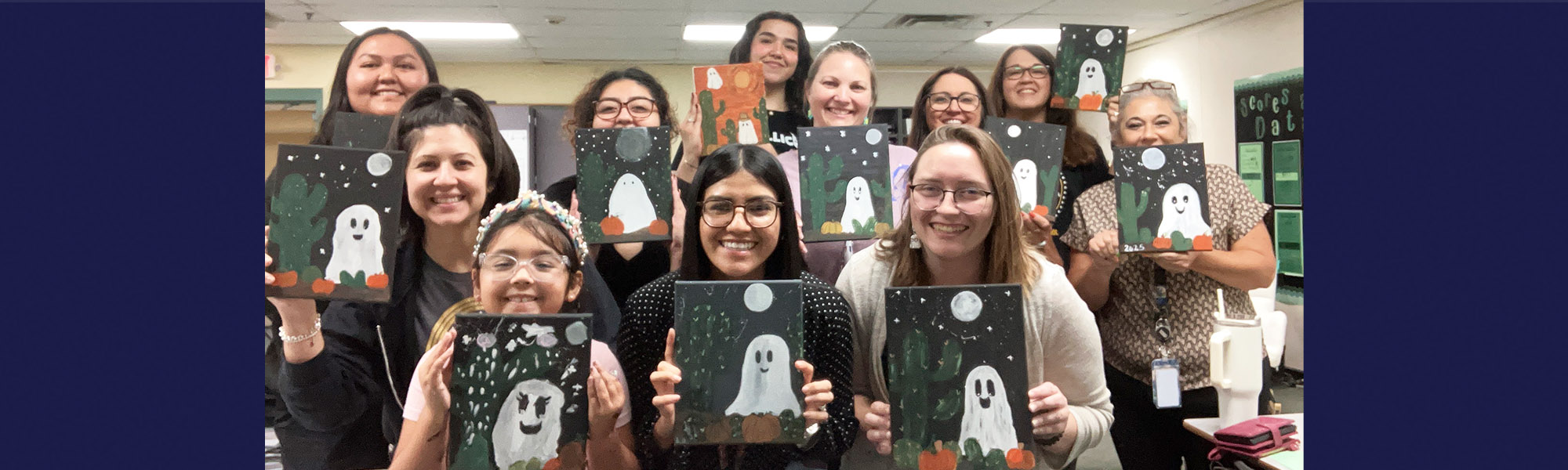 Group of happy students and adults holding up artwork