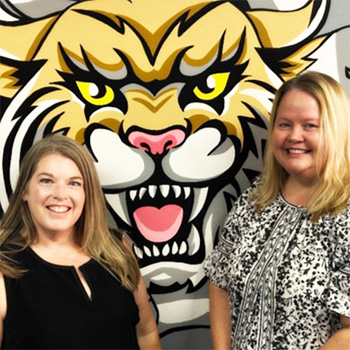 Two teacher in front of WVMS Wildcats mural
