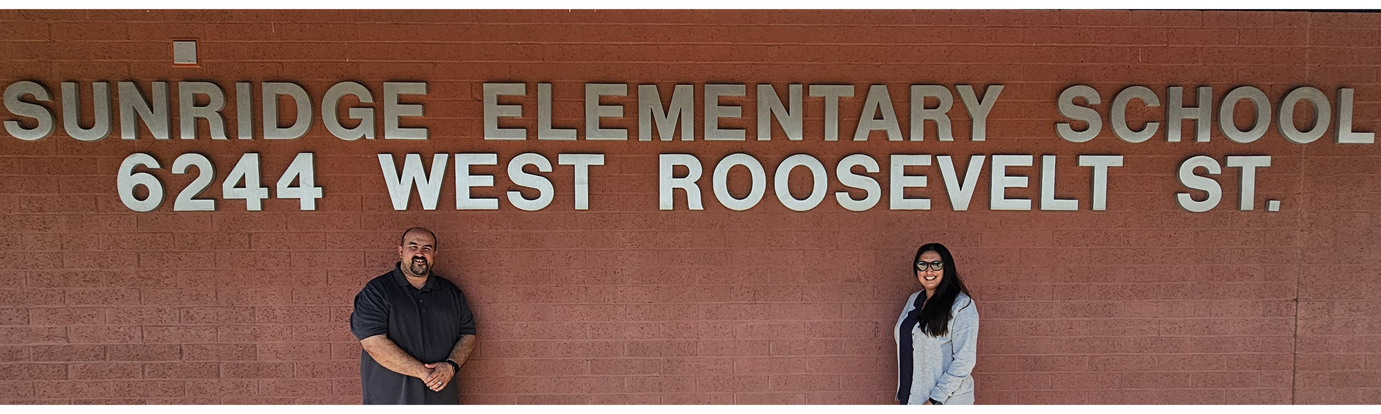 Staff standing under a sign that reads Sunridge Elementary School 6244 West Roosevelt St.