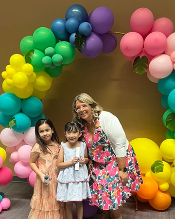 Staff with students holding certificates under colorful balloons