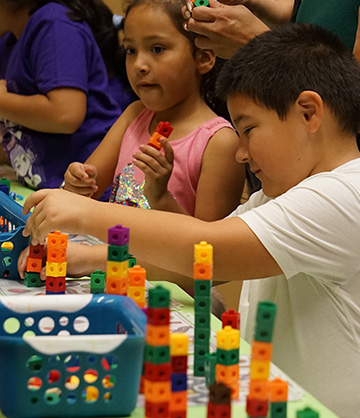 Adult helping students stack colored blocks