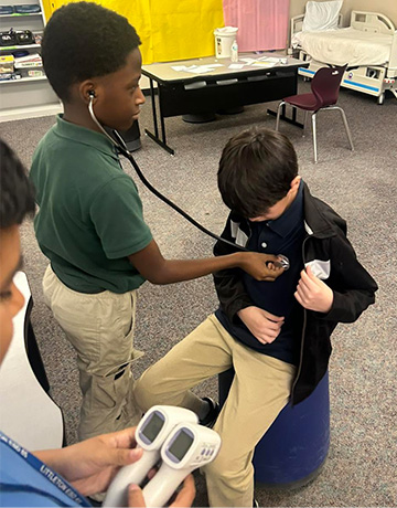 Student using a stethoscope to listen to another student's heart